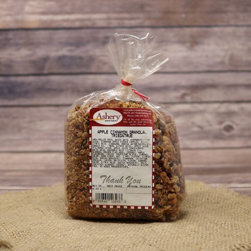 A clear bag of Tried And True Apple Cinnamon Granola sealed with a twist tie on rustic burlap with a wooden background.