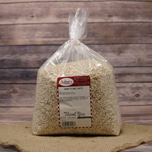 A bag of Baby Flake Oats, sealed with a twist tie, on rustic burlap with a wooden background.