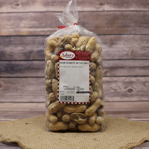 A clear plastic bag of Cajun Peanuts in the shell, closed with a twist tie and set on rustic burlap with a wooden background.