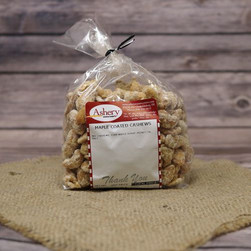 A clear plastic bag of Maple Coated Cashews, closed with a twist tie and set on rustic burlap with a wooden background.