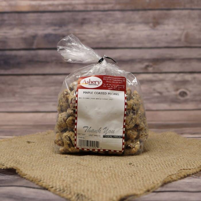 A clear plastic bag of Maple Coated Pecans, closed with a twist tie and set on rustic burlap with a wooden background.