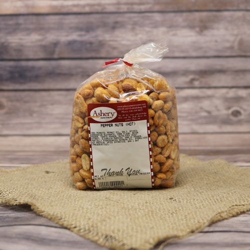 A clear plastic bag of Hot Pepper Nuts, closed with a twist tie and set on rustic burlap with a wooden background.