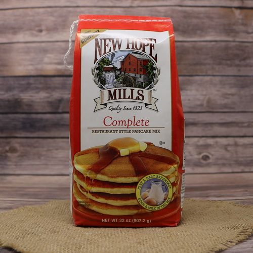 A tall red bag of Complete Pancake Mix on rustic burlap with a wooden background.
