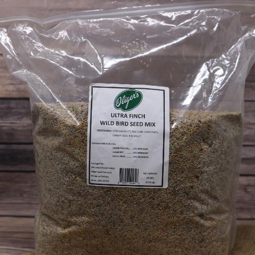 A large re-sealable bag of Ultra Finch Bird Seed on rustic burlap with a wooden background.