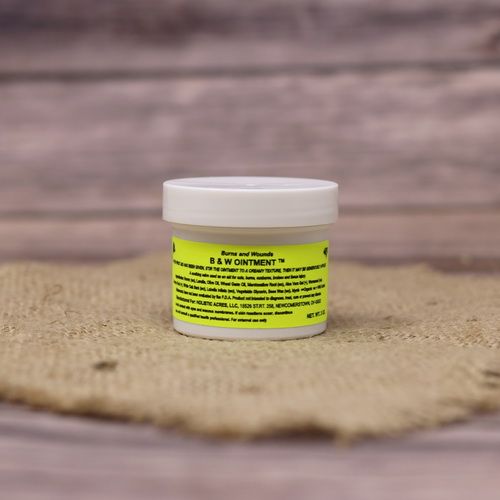 A 2 oz container with B&W Ointment, set on rustic burlap with a wooden background.