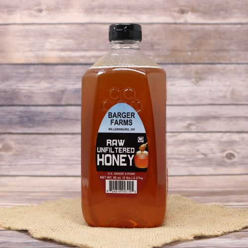 A 5lb bottle of Barger's Honey, on rustic burlap with a wooden background.