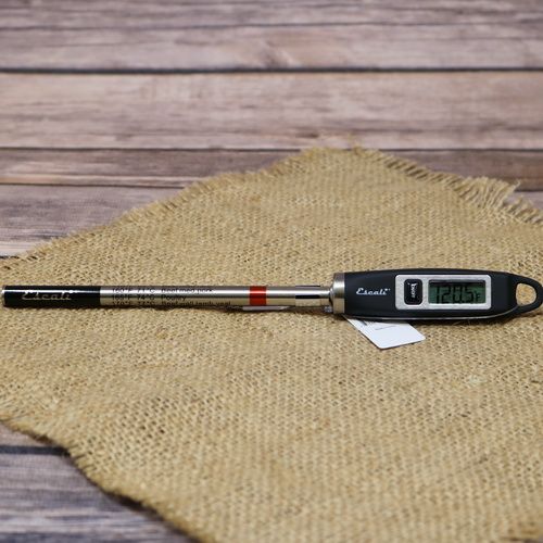 A digital thermometer laying on rustic burlap with a wooden background.