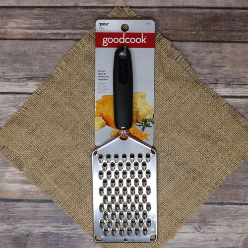 A handy stainless steel grater with a black handle, laying on rustic burlap with a wooden background.