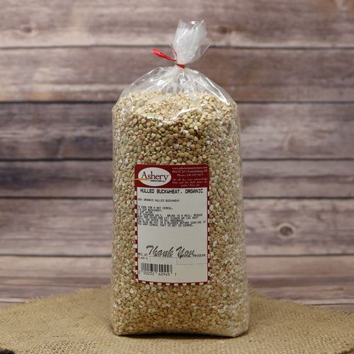 A bag of Hulled Buckwheat Organic, sealed with a twist tie, on rustic burlap with a wooden background.