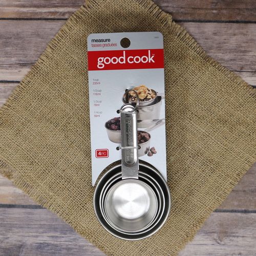 A set of 4 measuring cups, on rustic burlap with a wooden background.