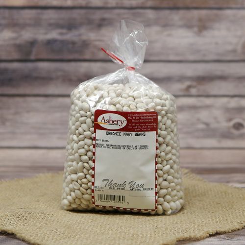 A clear plastic bag of Organic Navy Beans sealed with a twist tie on rustic burlap with a wooden background.