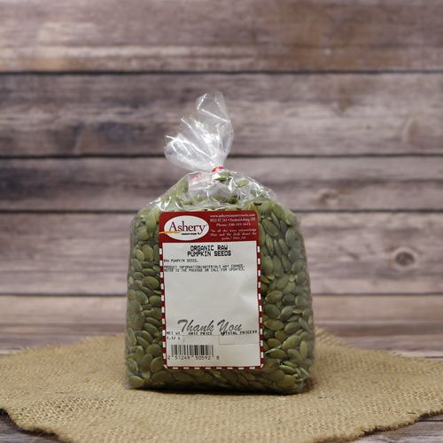 A plastic bag of Organic Raw Pumpkin Seeds, set on rustic burlap with a wooden background.