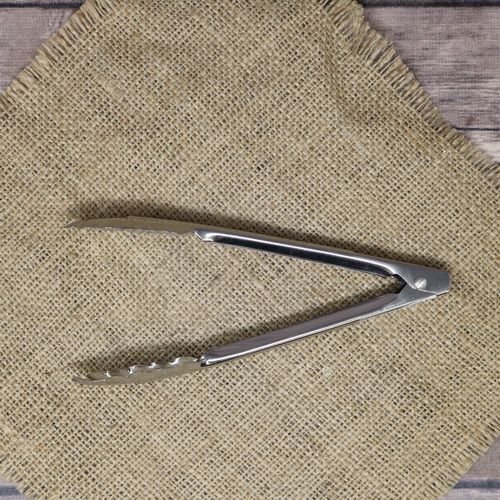 A stainless steel utility tong, laying on rustic burlap.