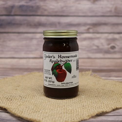 An 8oz glass jar of Yoder's Homemade Apple Butter, on rustic burlap with a wooden background.