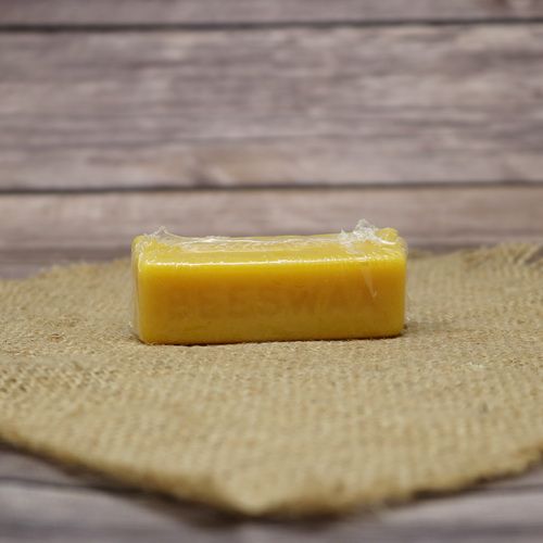 A 1 oz block of beeswax on rustic burlap with a wooden background.