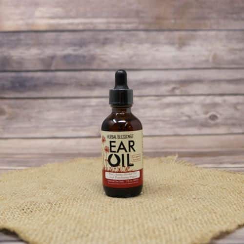 A 2oz dropper bottle of Herbal Blessings Ear Oil, set on rustic burlap with a wooden background.