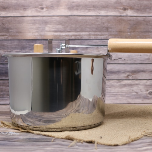 A stainless steel Whirley Popper on rustic burlap with a wooden background.