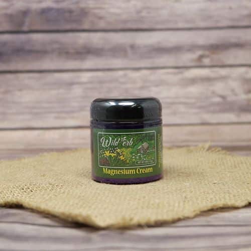 A 4 oz container of Wilderb Magnesium Cream, set on rustic burlap with a wooden background.