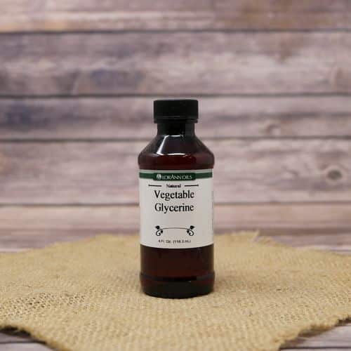 A 4 oz bottle of Vegetable Glycerine, set on rustic burlap with a wooden background.