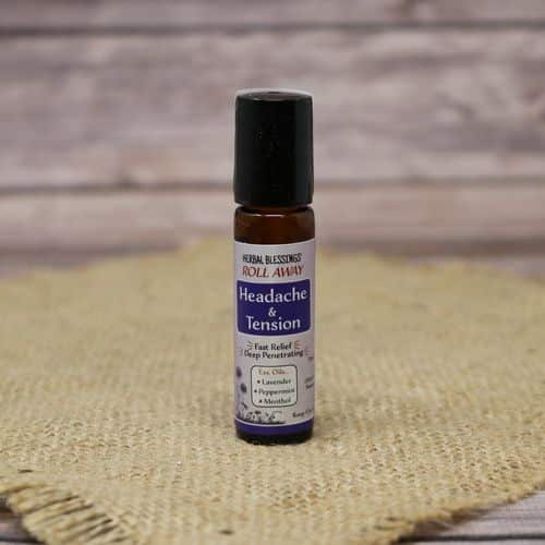 A roll on bottle of Herbal Blessings Headache & Tension Oil, set on rustic burlap with a wooden background.