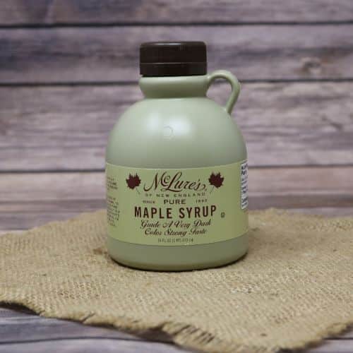 A 16 oz bottle of Very Dark Maple Syrup, set on rustic burlap with a wooden background.