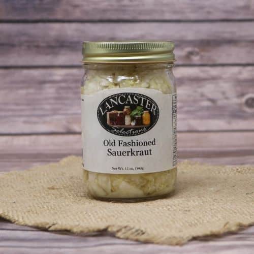 A pint size glass jar of Old Fashioned Sauerkraut, on rustic burlap with a wooden background.