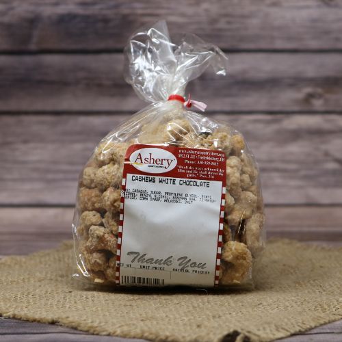 A plastic bag of White Chocolate Cashews closed with a twist tie, set on rustic burlap with a wooden background.