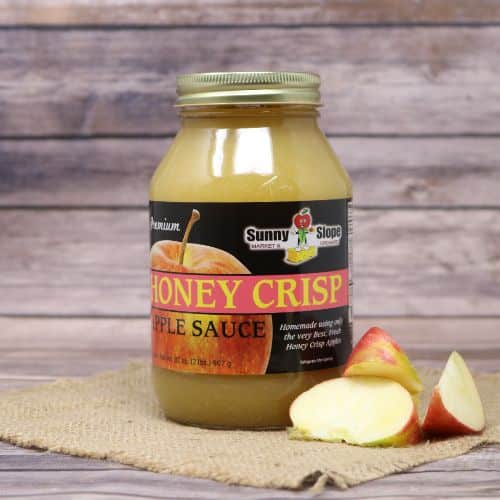 A quart size glass jar of Sunny Slope Orchards Honey Crisp Apple Sauce, on rustic burlap with a wooden background.