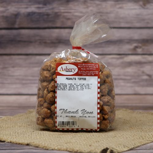A plastic bag of Toffee Peanuts closed with a twist tie, set on rustic burlap with a wooden background.