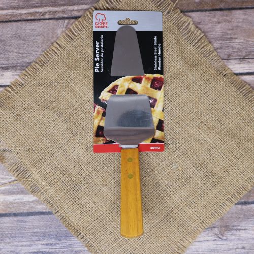 A Pie Server with a wood handle, laying on rustic burlap with a wooden background.