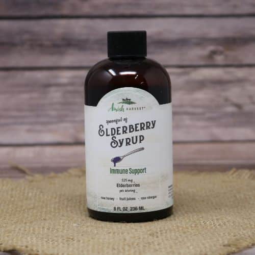 An 8 oz bottle of Elderberry Syrup, on rustic burlap with a wooden background.