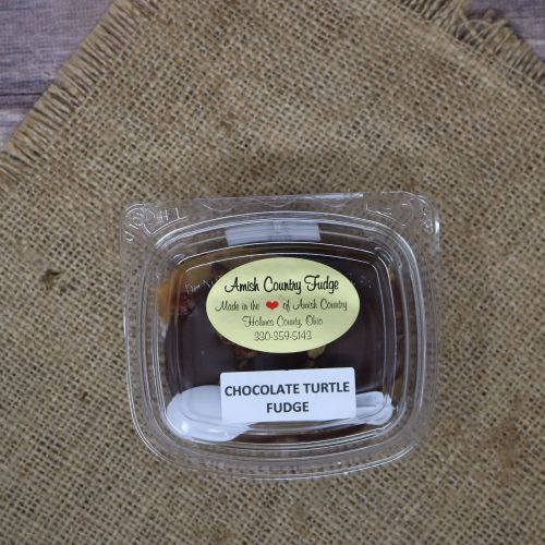 Clear plastic Ashery bowl with yellow sticker label on the plastic lid, filled with chocolate candies, sitting on a burlap material with wood background