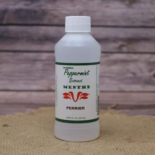 Small 8oz plastic bottle of liquid with a white and green sticker label, sitting on a burlap material with wood background