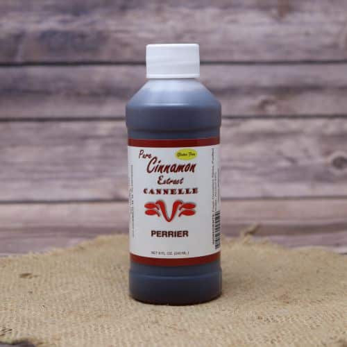 Small 8oz plastic bottle of brown liquid with a white and green sticker label, sitting on a burlap material with wood background