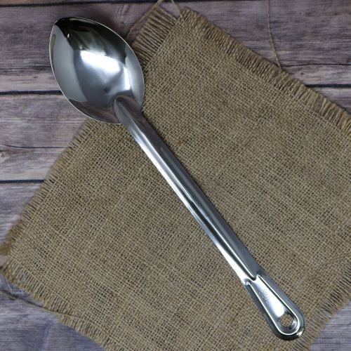 A stainless steel spoon laying on rustic burlap with a wooden background.