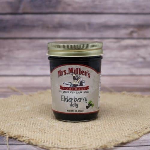 A 9oz glass jar of Mrs. Miller's Elderberry Jelly with no sugar added, on rustic burlap with a wooden background.