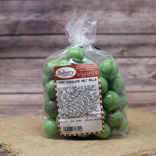 Bag of Ashery Mint Chocolate Malt Balls, with a green hue, tied with a twist, on a burlap and wooden surface.