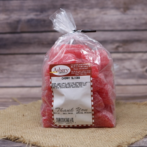A bag of vibrant red cherry slices candy, secured with a twist tie and placed against a straw mat and wood panel backdrop