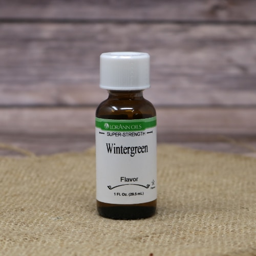 Bottle of LorAnn Super-Strength Wintergreen Flavor, 1 fl oz size, against a burlap and wooden backdrop.