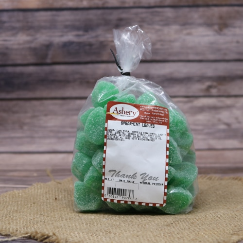 A bag of Ashery spearmint leaves candy, in a rich green color, tied at the top and set on a textured straw mat with a wooden background.