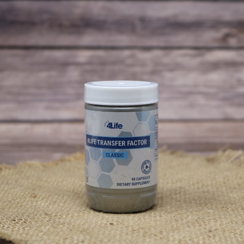 Bottle of 4Life Transfer Factor Classic dietary supplement on a burlap mat with a rustic wooden background.