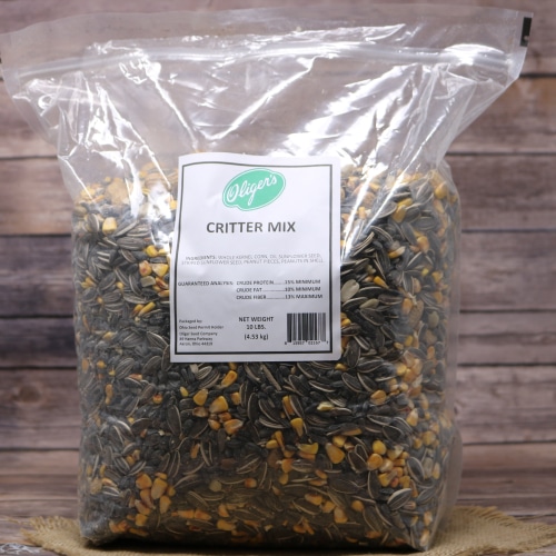 A large plastic bag of Critter Mix with a green and white label, filled with a blend of seeds and grains, on a wooden surface.