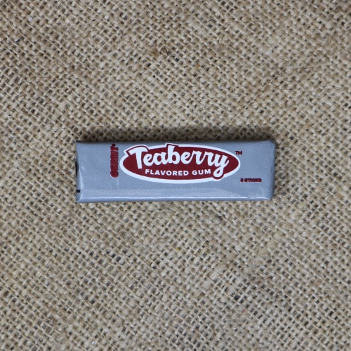 Unopened pack of Teaberry flavored chewing gum on textured burlap fabric.