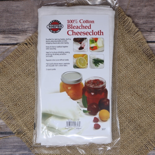 Pack of Norpro 100% cotton bleached cheesecloth on rustic burlap, with a wooden background and images of its uses on the packaging.
