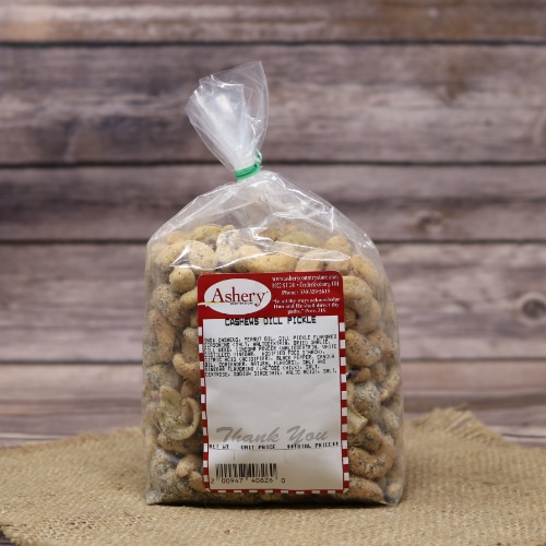 A plastic bag of Dill Pickle Cashews closed with a twist tie, set on rustic burlap with a wooden background.