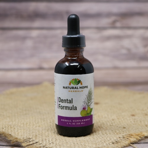 A glass bottle with a squeeze dropper of Dental Formula Supplement by Natural Hope Herbals on rustic burlap with a wooden background.