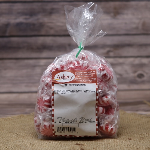 A clear plastic bag of red and white Peppermints Sugar Free sealed with a green twist tie on rustic burlap with a wooden background.