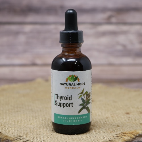 A small glass bottle with a squeeze dropper of Thyroid Support Supplement on a rustic burlap with a wooden background.