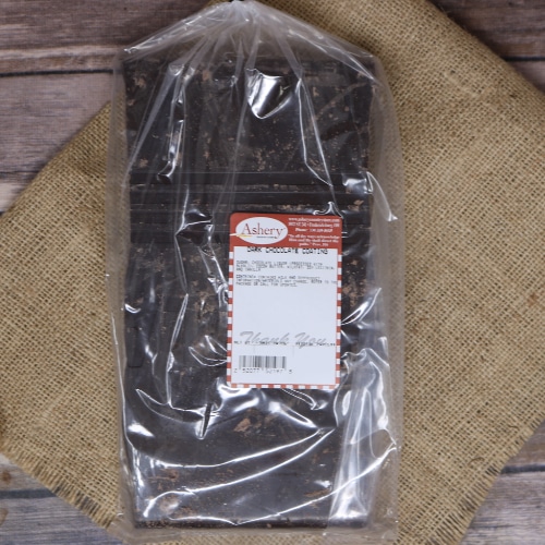 A clear plastic bag containing a slab of Dark Chocolate Coating sealed with a twist tie on rustic burlap with a wooden background.