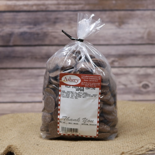 A clear plastic bag of Milk Chocolate Coating Wafers sealed with a twist tie on rustic burlap with a wooden background.
